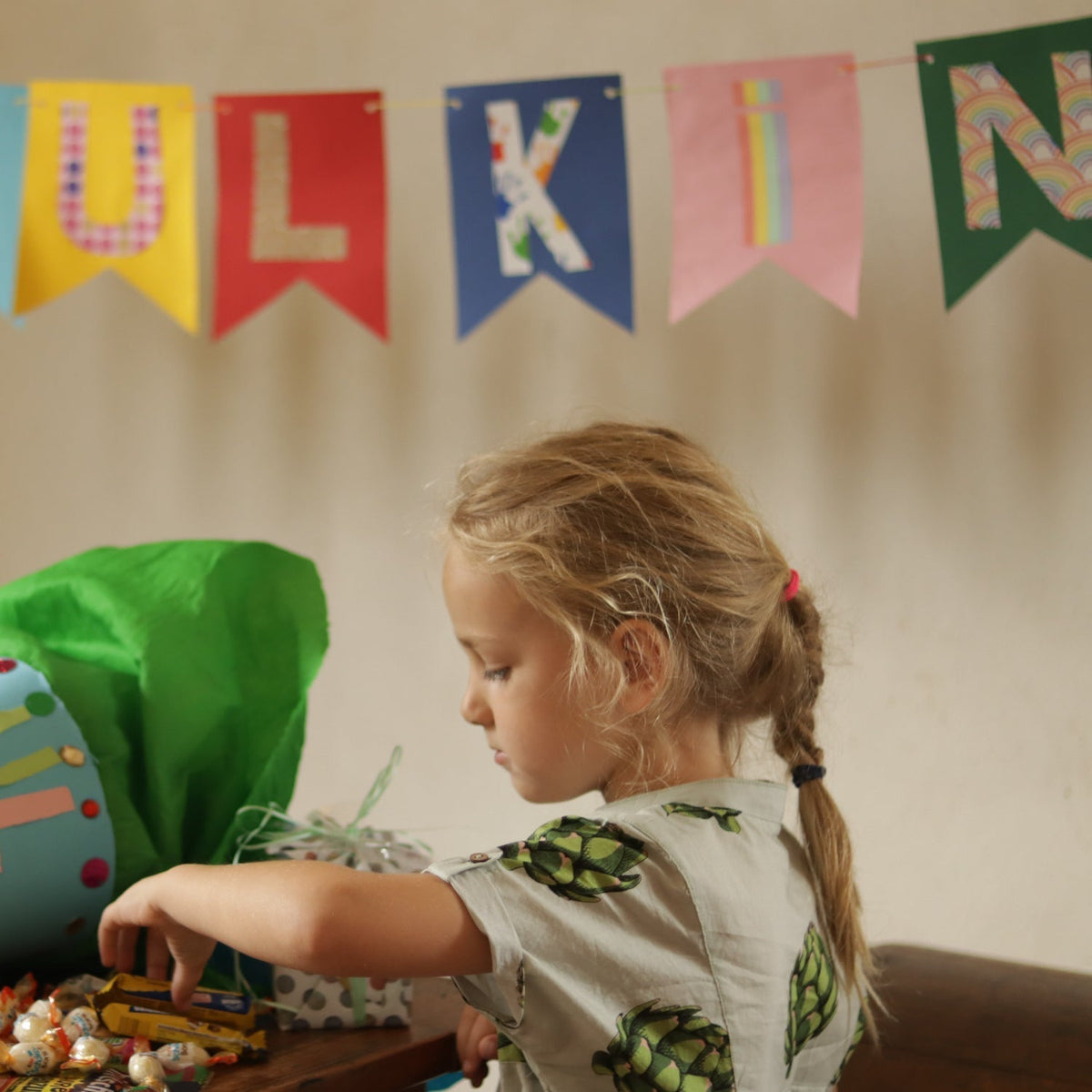 Kind im selbstgenähten Holunder-Hemd mit grünen Artischocken am Geschenketisch zur Einschulung